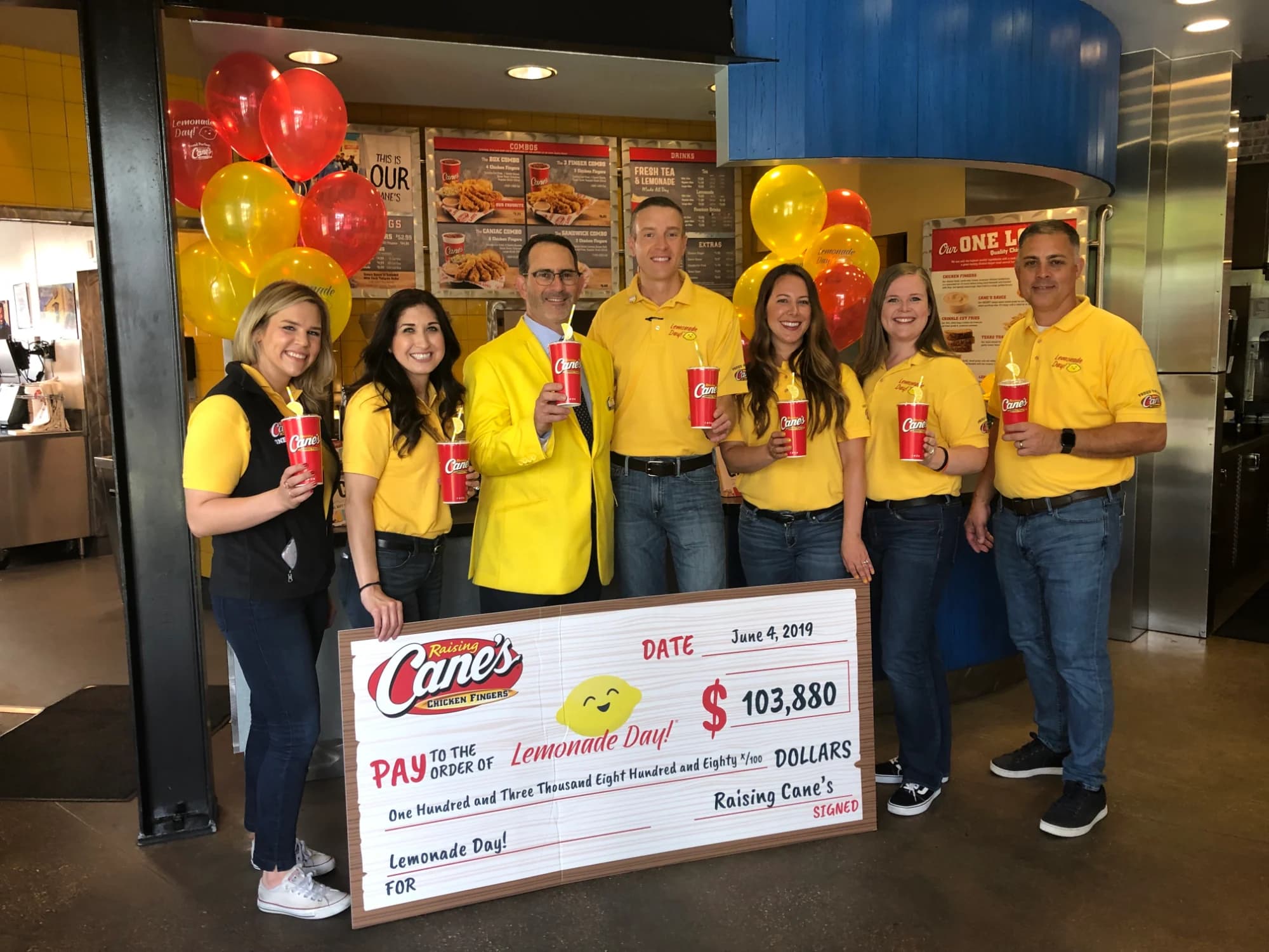 The Raising Cane's team presenting a sponsorship check
