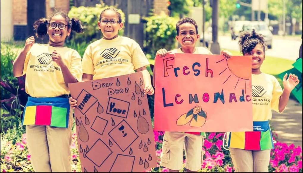 A kid holding up a hand-painted lemonade stand sign