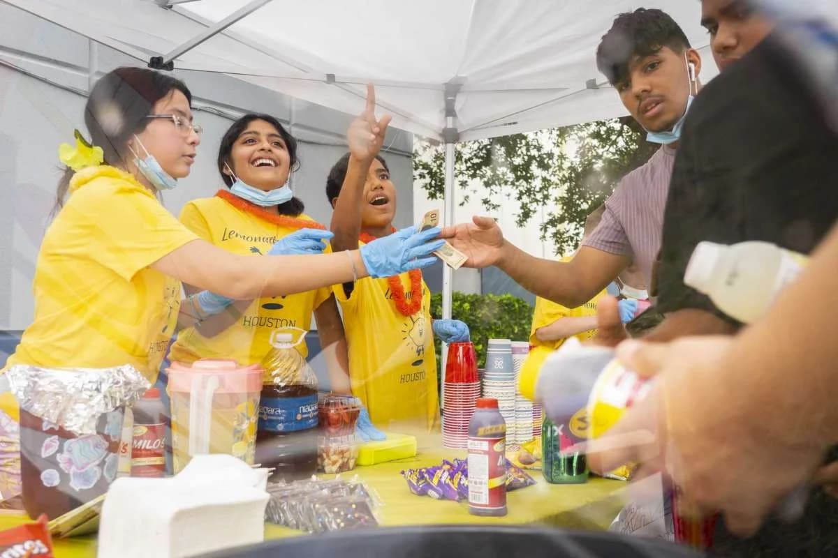 Kids mixing lemonade together at a stand