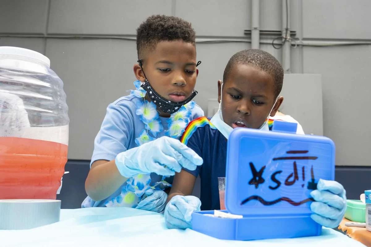 Two boys counting tips in a blue box