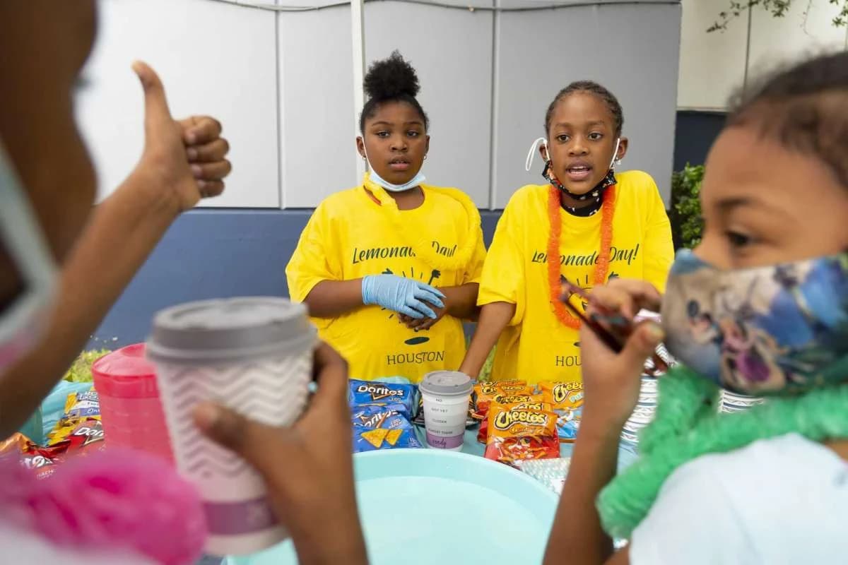 Kids cheering behind their lemonade stand