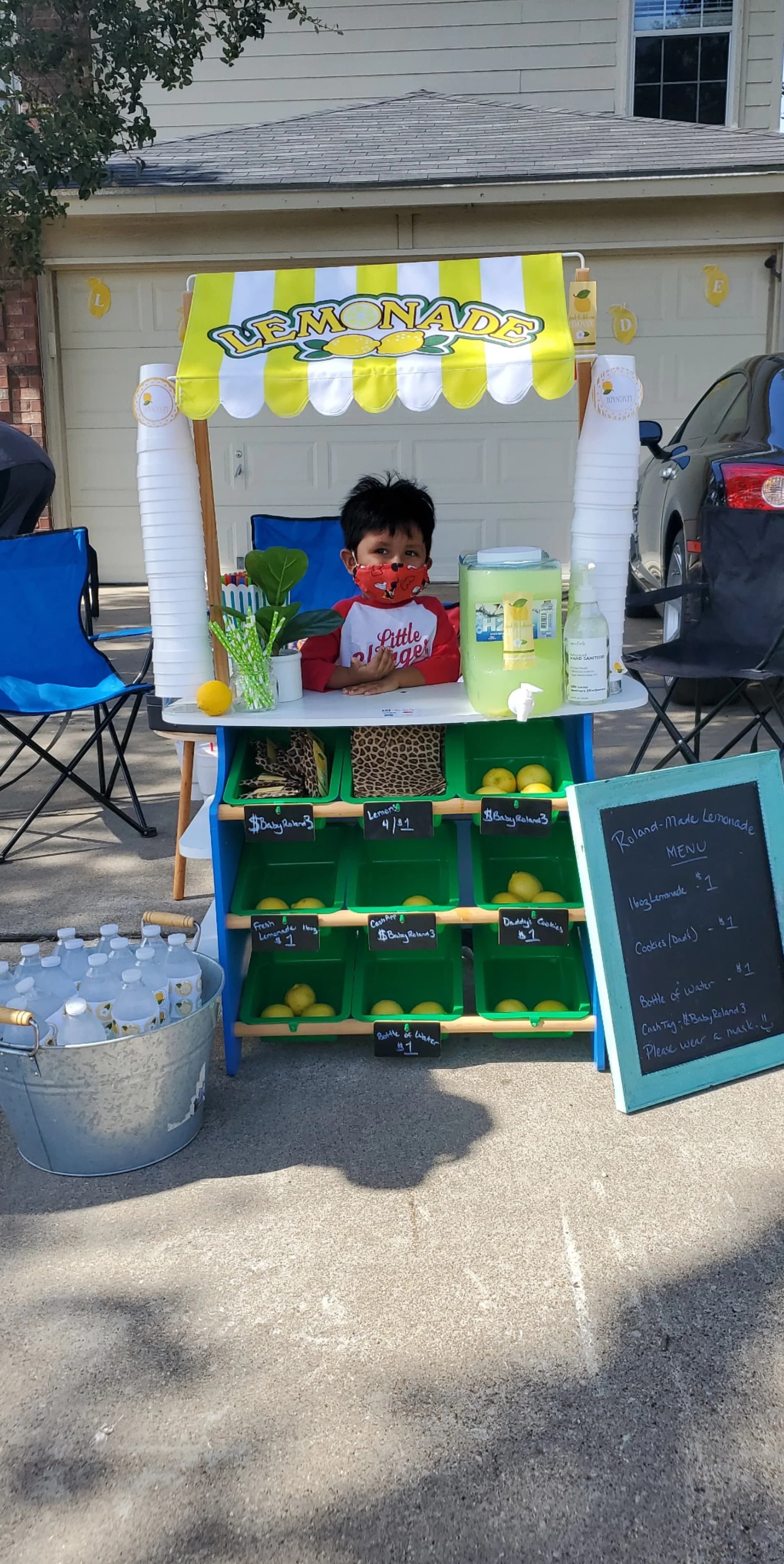 A boy at a lemon-decorated stand on his front porch